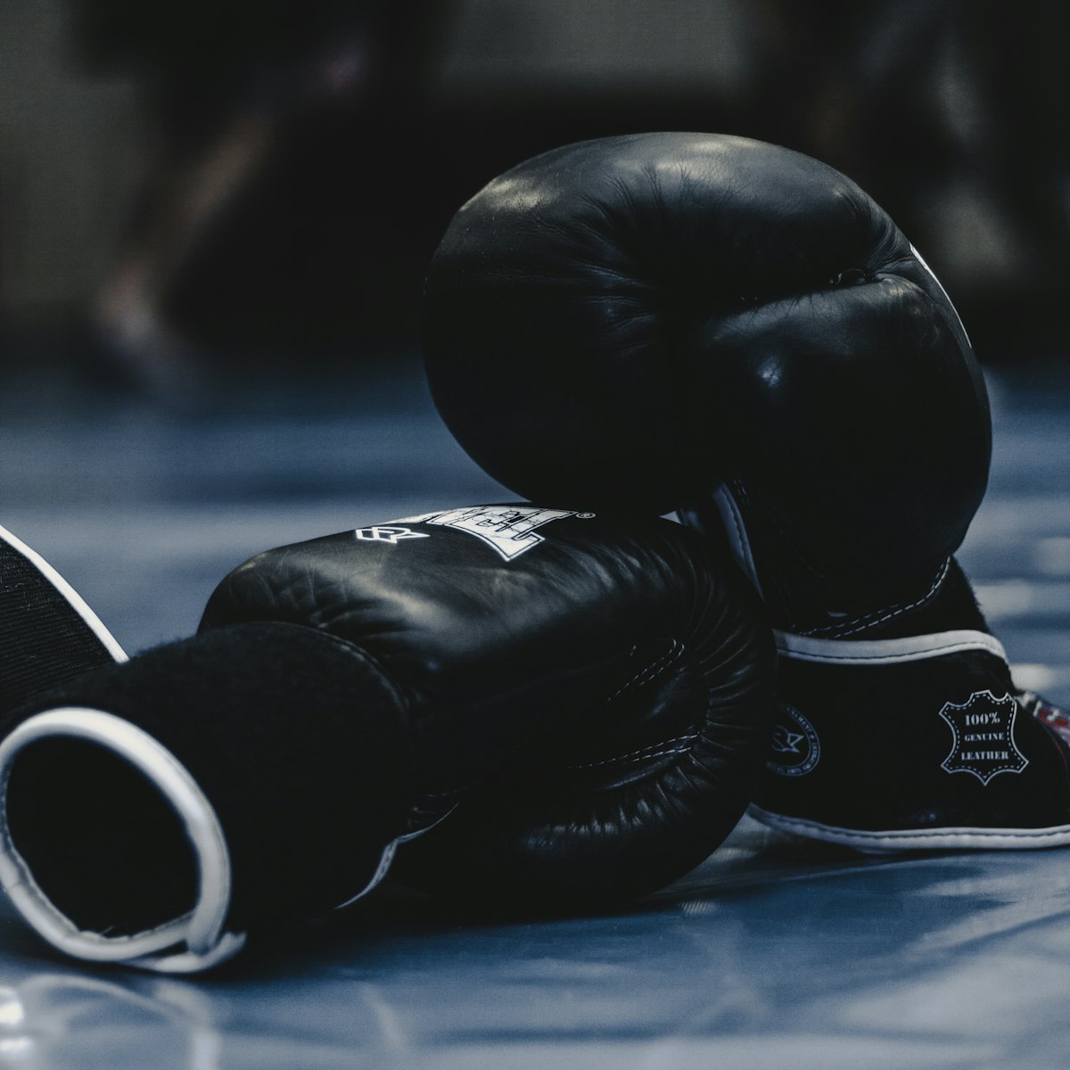 A pair of black leather boxing gloves resting on the mat